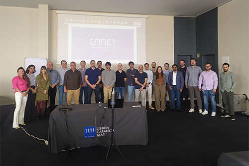 A group of Enact project partners, standing in a room with the Enact logo projected on the wall behind them.